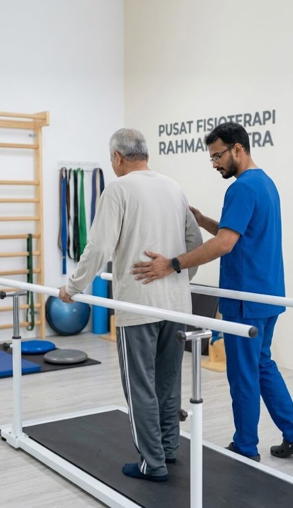 Certified physiotherapist assisting a post-stroke patient with supervised gait retraining at Pusat Fisioterapi Rahman Putra, Sungai Buloh.