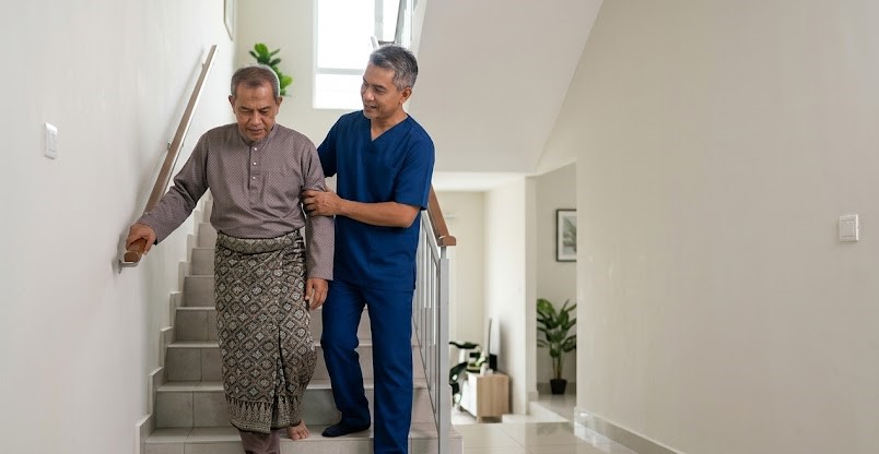 Physiotherapist training a stroke patient on stair negotiation for a typical Malaysian terrace house environment in Sungai Buloh.